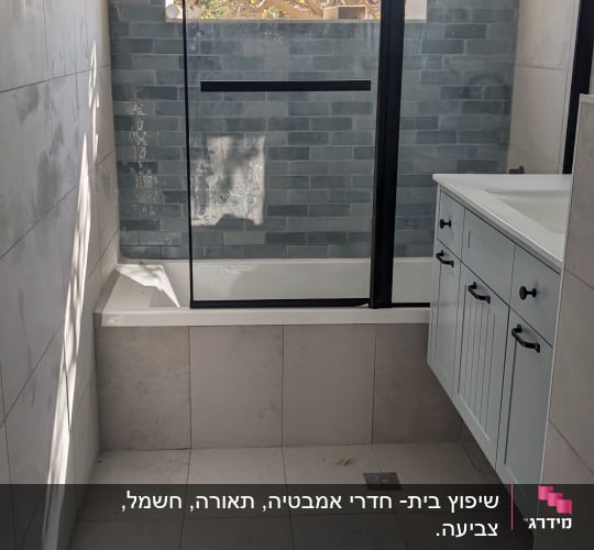 חדר אמבטיה עם אריחים חדשים ודלת זכוכית